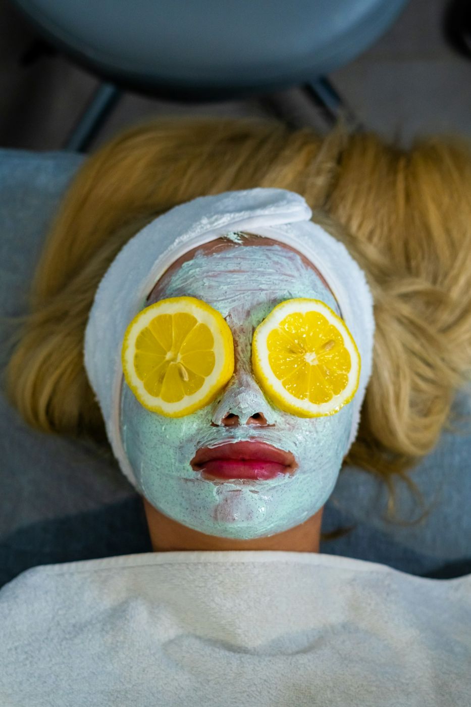 Imagen de referencia: mujer con mascarilla facial y rodajas de limón sobre los ojos